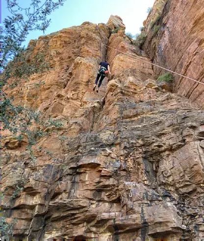 Climber on a top rope on a layered rock crag