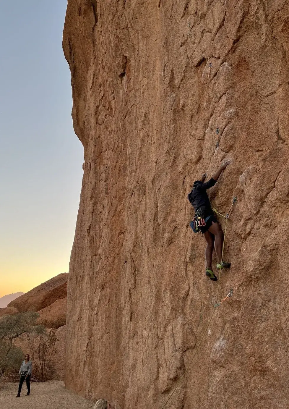 Climber high on a granite wall at Spitzkoppe, with the belayer at the base