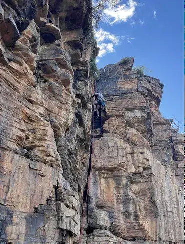 Climber in a crack on a tall layered rock wall