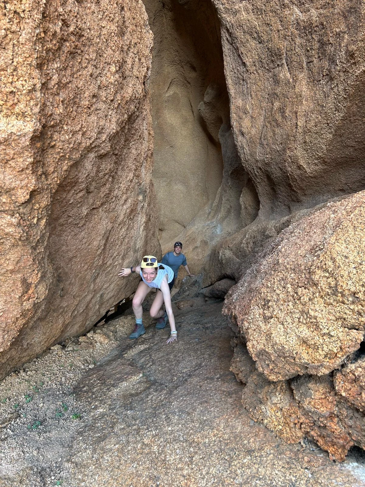 Hikers scrambling through a sheltered arched granite cave formation at Spitzkoppe